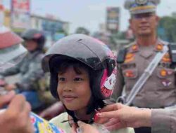 Seorang Anak Tersenyum, Saat Satlantas Polresta Barelang Membagikan Helm Secara Gratis di Operasi Keselamatan Seligi 2025